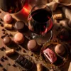 Luxe wijn en chocolade pairing met rode wijn, truffels en macarons op houten achtergrond in warm gouden licht